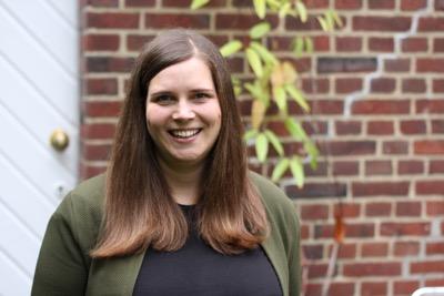 Erzieherin Jenne lächelt warmherzig in die Kamera; im Hintergrund eine Backsteinwand