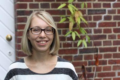 Erzieherin Ann-Christin lächelt warmherzig in die Kamera; im Hintergrund eine Backsteinwand